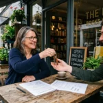 Photo naturelle de l’entrée d’un commerce, échange de clés de main à main et documents de bail sur table – Compta Resto
